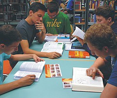 Schüler sitzen an einem Tisch in der Bibliothek und lesen Bücher