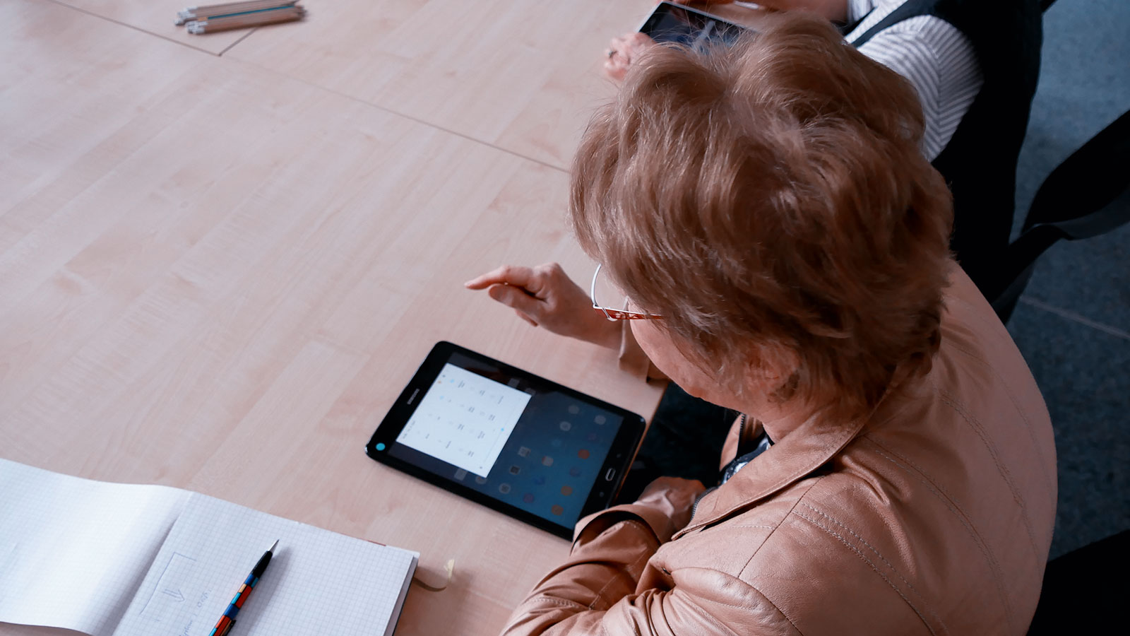 Frau sitz an einem Tisch und vor ihr liegt ein eBook