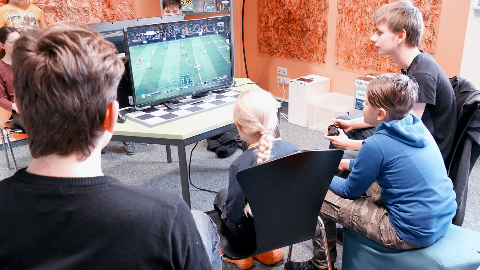 Vier Kinder spielen Fifa auf einer Playstation Konsole