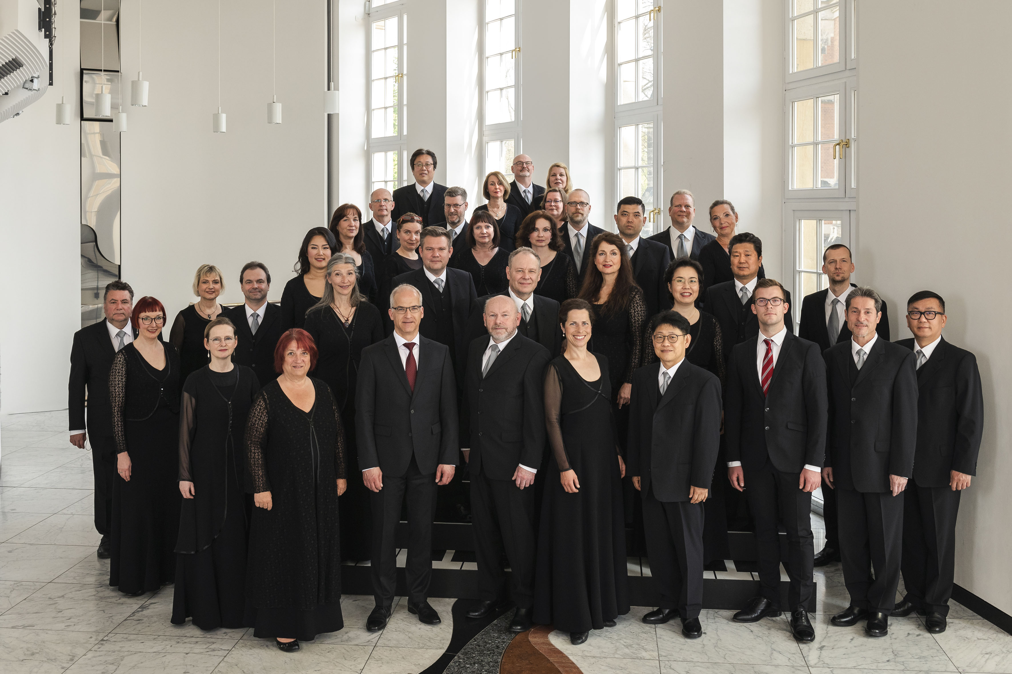 Foto der Mitglieder des Chemnitzer Opernchores, alle Chormitglieder sind schwarz gekleidet und stehen im Rangfoyer des Opernhauses